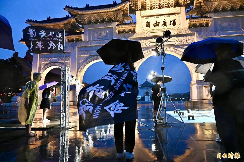 民眾批著「光復香港 時代革命」旗幟參加活動。（記者塗建榮攝）