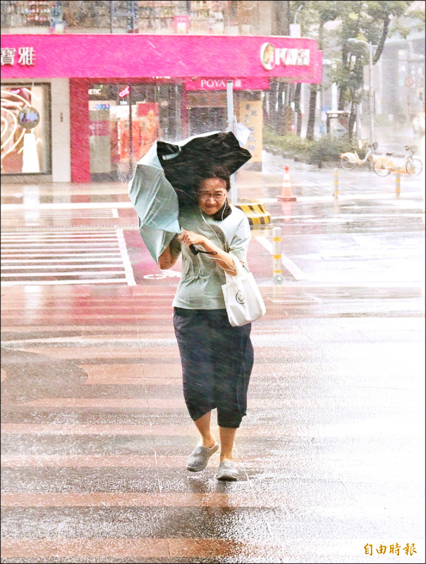 台北昨風雨交加,民眾持雨傘吃力地往前走。(記者方賓照攝)