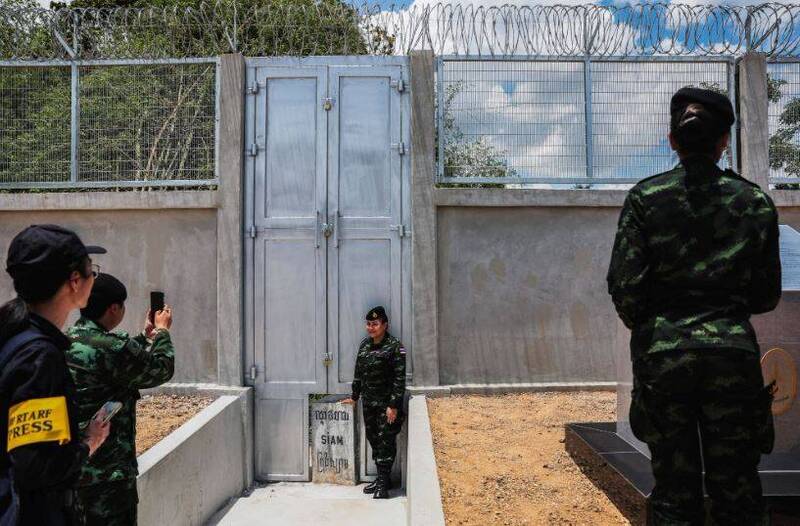 泰国士兵在泰柬边境围栏的大门底部，一块刻有「暹罗」字样的标志旁拍照。（路透）