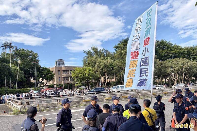 台灣國理事長陳峻涵25日站在監察院大門前，高舉「民眾黨變小國民黨，白色力量變跟屁蟲」標語，反諷民眾黨及現場抗議的群眾。（記者陳治程攝）