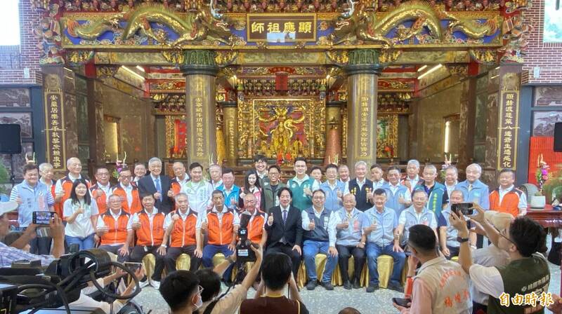 總統兼民進黨主席賴清德(前排中,穿黑西裝)今早由該黨桃園市長參選人黃世杰(中右)等人陪同,前往龜山區顯安巖顯應祖師廟上香參拜,祈求國泰民安、風調雨順及庇佑黃世杰勝選市長,祖師廟管委會主委黃宏洋(中左)及團隊、信徒熱情接待。(記者陳璟民攝)