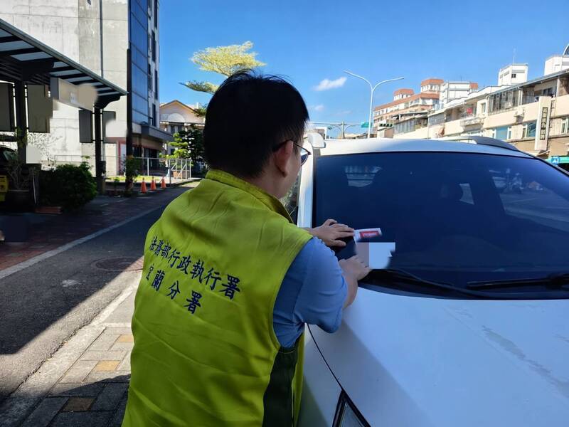 行政执行署宜兰分署人员在欠税车辆上贴封条。（图由行政执行署宜兰分署提供）