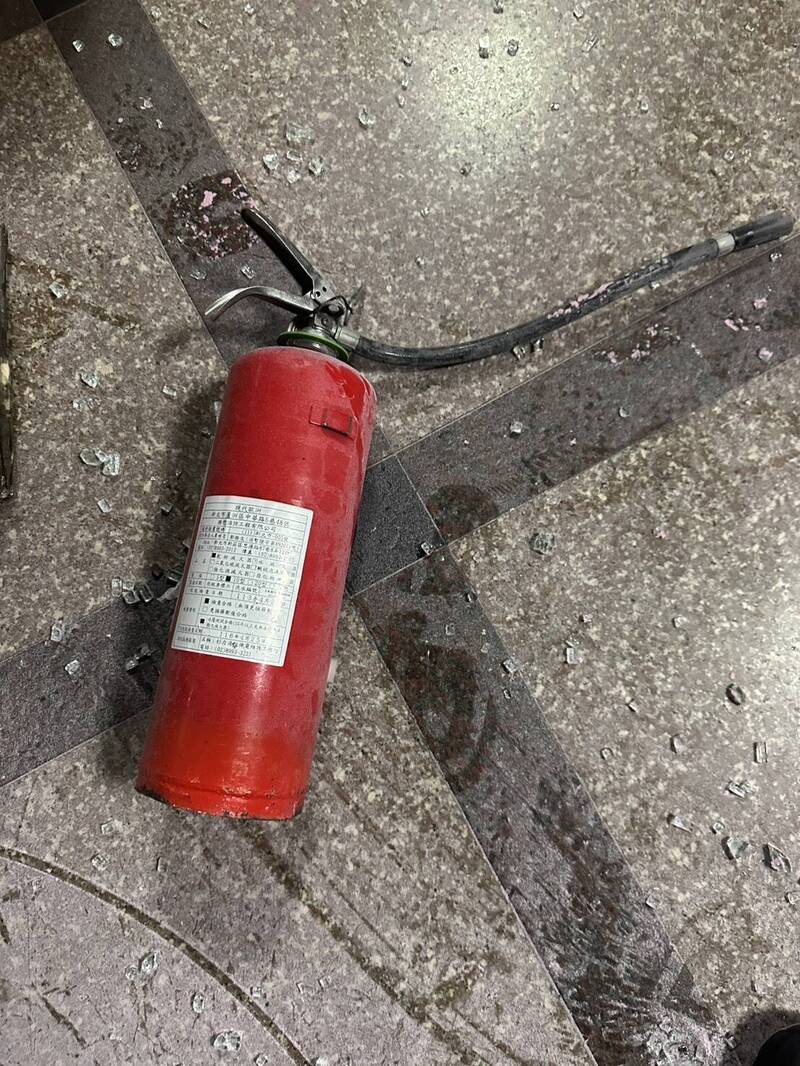褚男持灭火器砸大门玻璃。（记者徐圣伦翻摄）