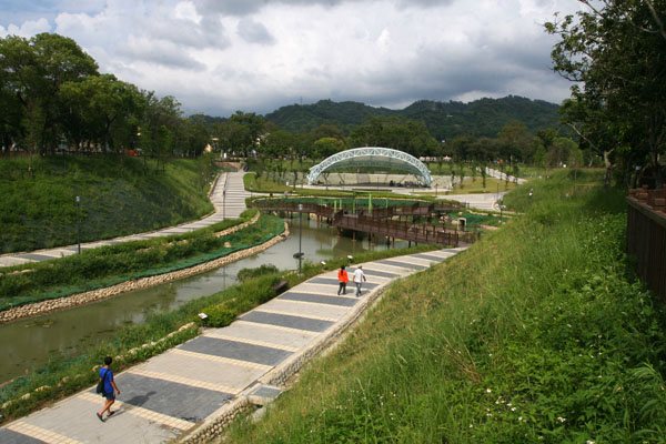 以多功能設計的大型公園，美麗的生態池映著遠處的山景與綠樹，充滿優閒氛圍。