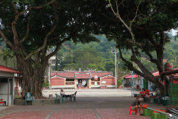 古厝前有左右兩棵大榕樹及大廣場，在地人坐在榕樹下乘涼，愜意不已。