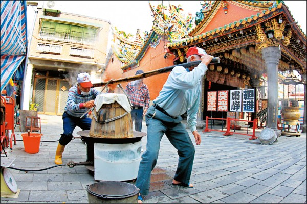 傳統以檜木桶炊蒸完成米糕後，得靠兩人合力扛上肩移往拌桶旁，才能進行下個步驟、將食材攪拌均勻。(圖片提供／社大李青純)