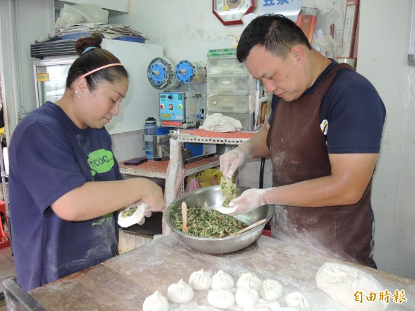楊金學夫婦一起為水煎包裝填餡料，每個細節絲毫不馬虎。（記者翁聿煌攝）