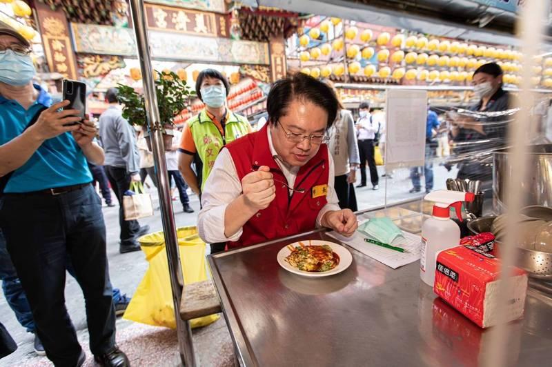 基隆市廟口夜市是庶民美食的天堂，圖為廟口夜市內知名的碳烤蚵仔煎，基隆市長林右昌正在品嘗蚵仔煎美食。（資料照，基隆市政府提供）