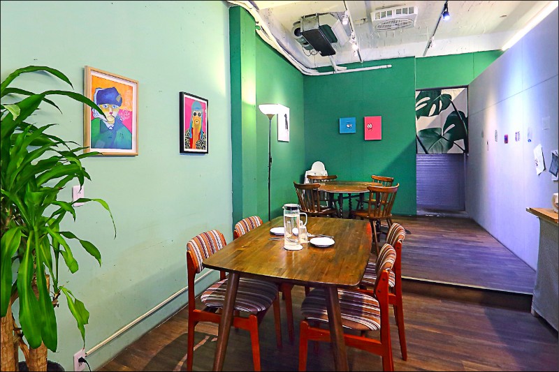 店內的用餐空間以充滿綠意的綠色調為主，並且牆上掛滿老闆親自挑選的藝術畫作，整體空間非常愜意舒服。（記者李惠洲／攝影）