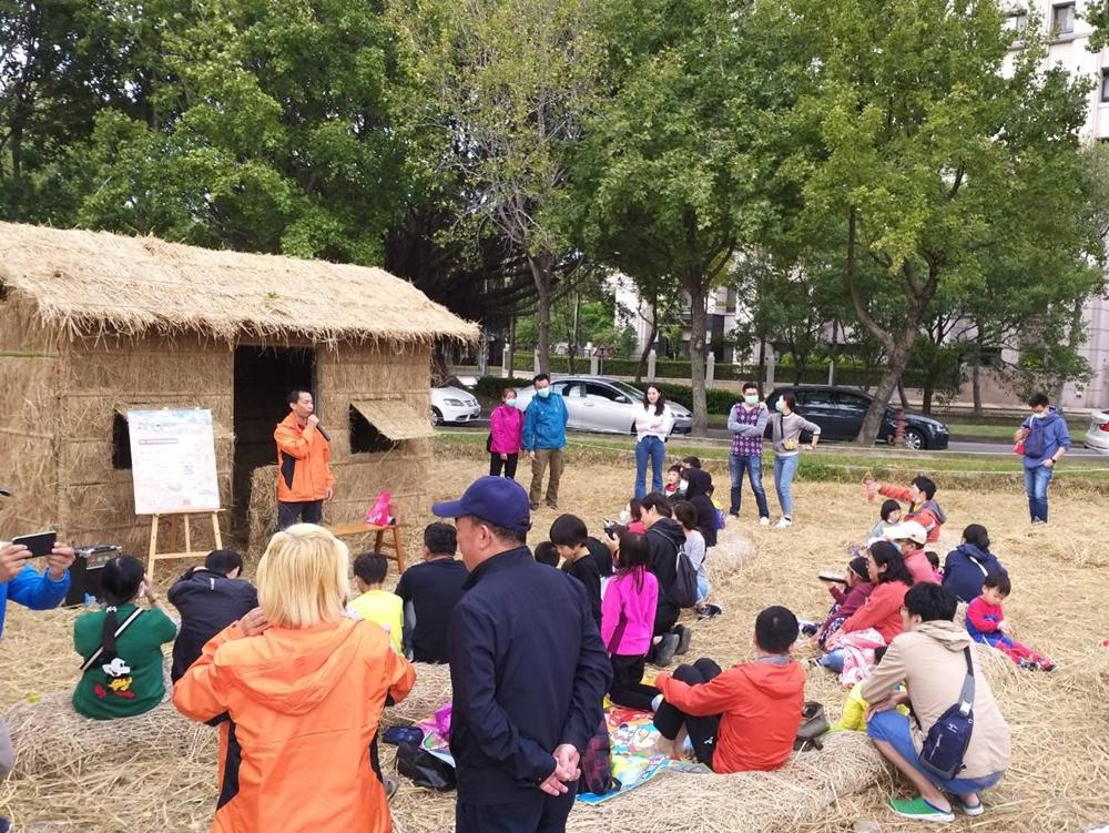 竹北新瓦屋的「水稻田生態教育園區」內的稻草故事屋，大人小孩坐在草捲上聽故事。（記者黃美珠攝）