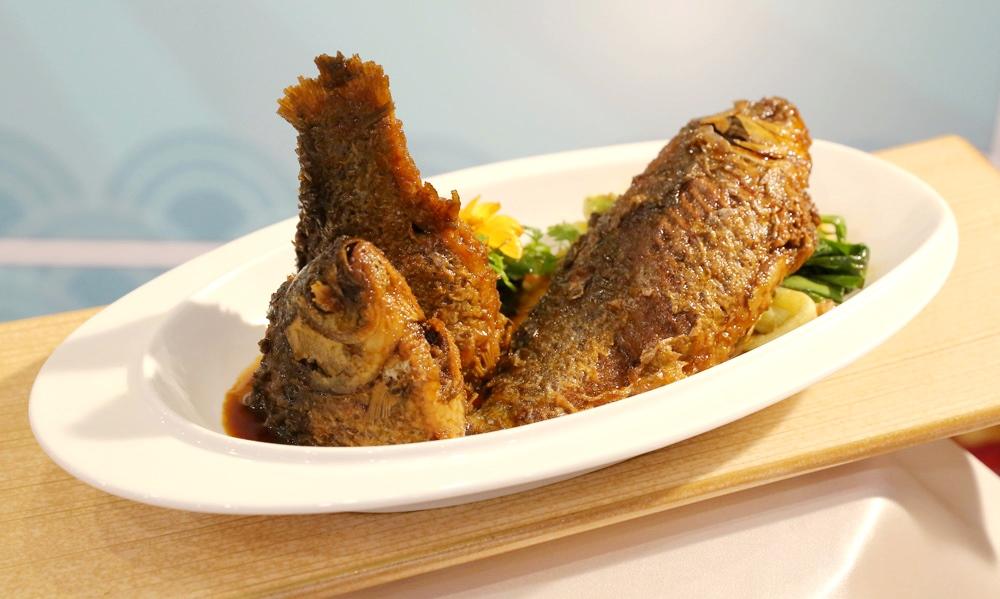 本幫名菜「蔥㸆鯽魚」將尾鯽魚煎定型後與大蔥冰糖醬油同㸆燒，魚骨酥化蔥香滲肉。（圖／台南台糖長榮酒店提供）