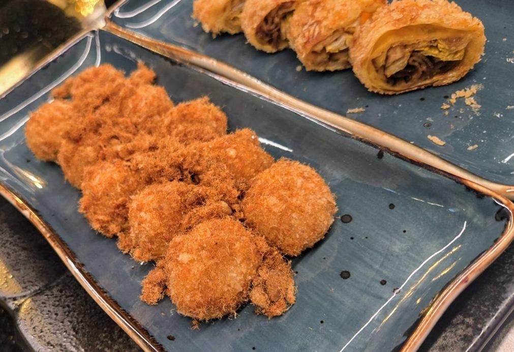 「鴨香米糕芝丸揚」將紅蟳米糕結合義式炸飯糰概念，內餡包入蟹肉與起司，以鴨油高溫酥炸後裹上肉鬆。（圖／記者王捷攝）