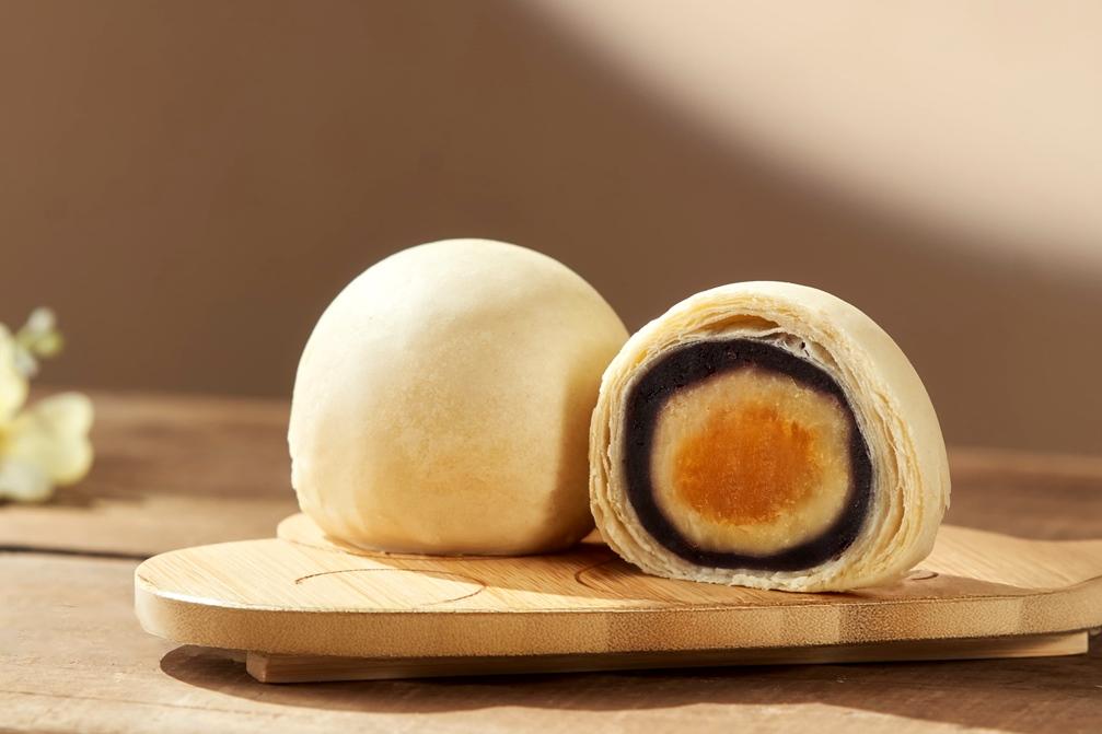 「白玉金藏」外層白潤酥皮，中層紫薯綿密，中心　為金黃鹹蛋黃製成細粉，細緻揉入綿密白豆沙，層層疊疊鹹香濃郁卻不膩。（圖／品牌提供）