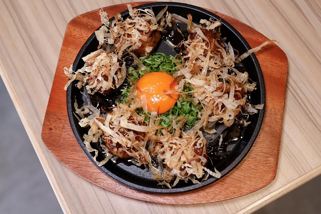 「鐵板雞肉丸子」售價280元，取雞胸、雞腿肉，搭配雞軟骨、生紫蘇葉等食材製成雞肉丸，淋上烤肉醬搭配生蛋黃上桌。（圖／記者郭宣暄攝）
