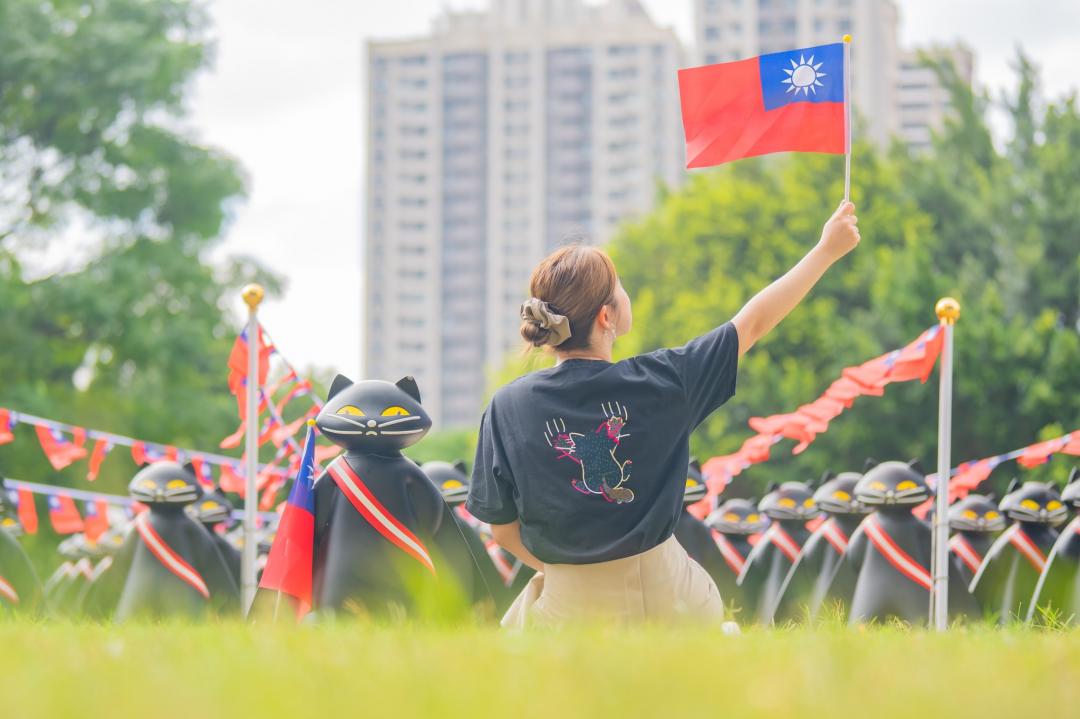 手舉國旗與黑貓拍照打卡，格外亮眼可愛。（圖／翻攝自桃園市民政局FB）