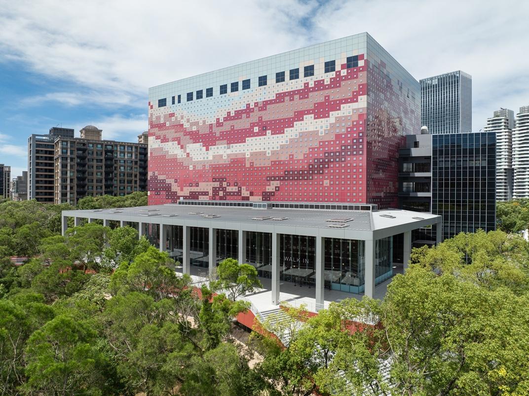 國家檔案館建築色系融入林口紅土的特色，以烤漆玻璃與鏡面不鏽鋼片堆疊方式點綴立面層次。