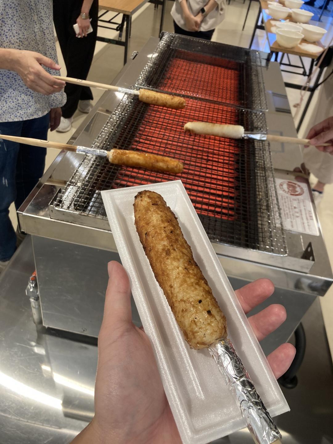 秋田代表美食「烤米棒」，將秋田米飯均勻包覆在木棒，烤到近「恰恰」，再塗上醬口感外脆內嫩。（記者楊綿傑）