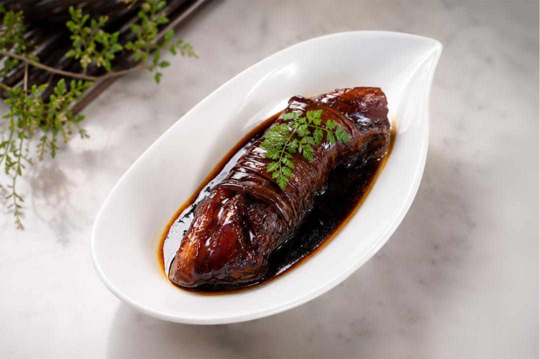 「稻草札天麴肉」源自上海金澤非遺菜餚。選用天麴豬以稻草綑綁，加紅麴與啤酒慢火燉煮。（業者提供）
