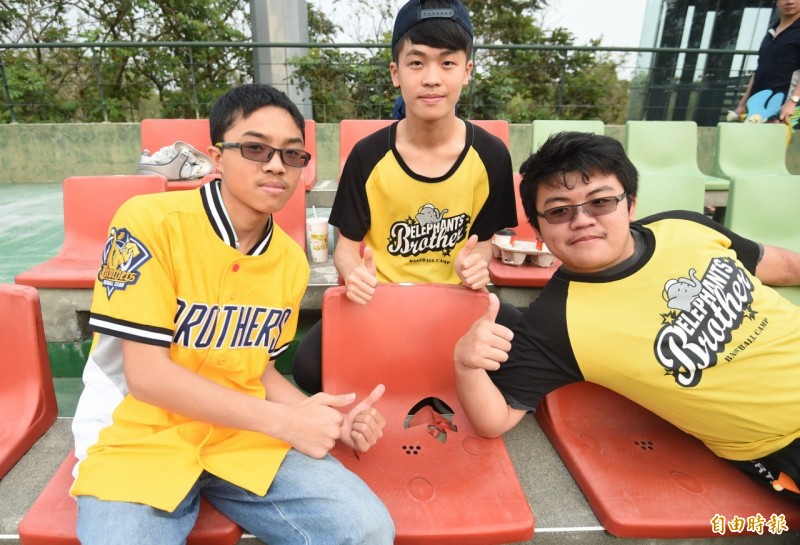 球迷搶跟許基宏炸裂的外野看台椅子合照。（記者廖耀東攝）