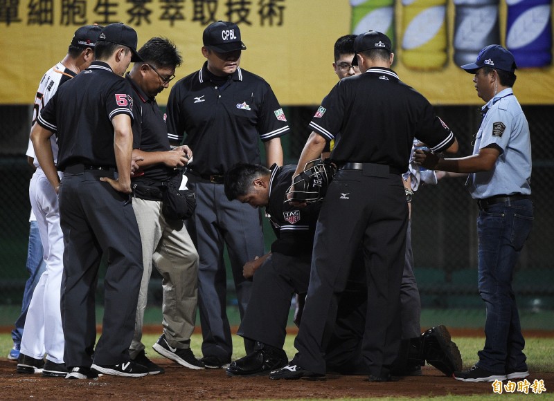 主審尤志欽（中）遭球擊中，痛苦跪地下場治療。（記者陳志曲攝）
