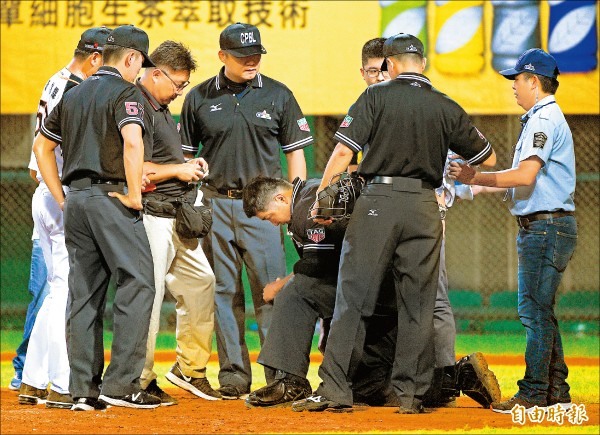 主審尤志欽（中）遭球擊中，痛苦跪地下場治療。（記者陳志曲攝）