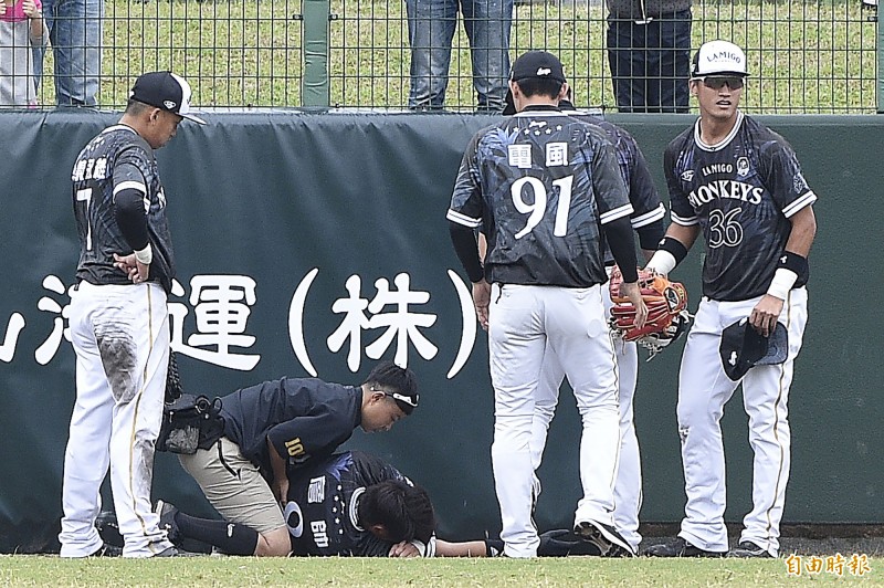 Lamigo桃猿詹智堯（中）為了接飛球撞上全壘打牆，隨後痛苦倒地。（記者陳志曲攝）