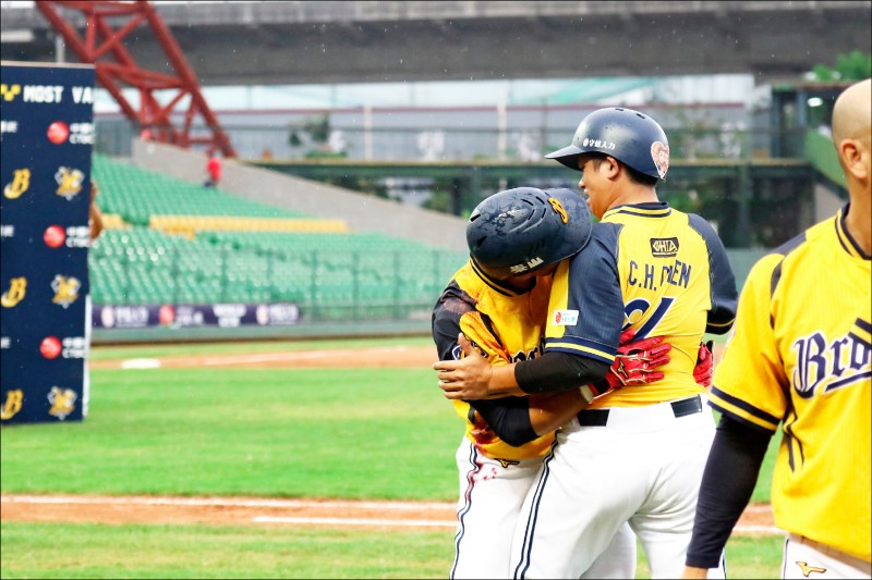 敲出再見安打的王勝偉（左）接受隊友「洗禮」後，故意擁抱好友陳江和（右）。（中信兄弟提供）