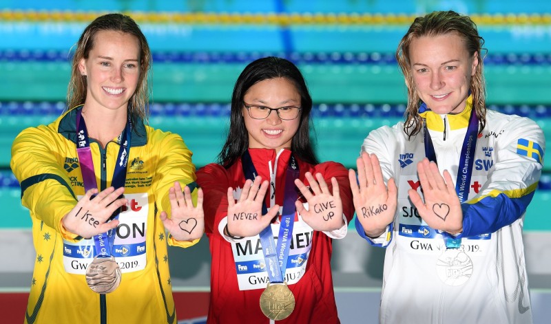 在蝶式奪牌的3位選手，直播在掌心祝福句子，合拚出「池江璃花子，請永遠不要放棄」，為罹癌的日本美少女打氣。（法新社）