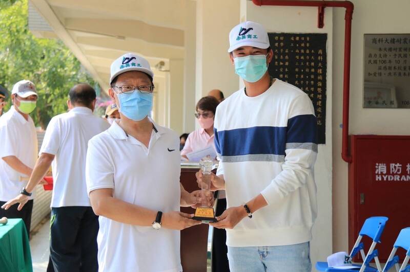 黃子鵬獲得南英傑出校友肯定，他也從南英校長陳志隆手中獲頒獎座。（陳献榮提供）