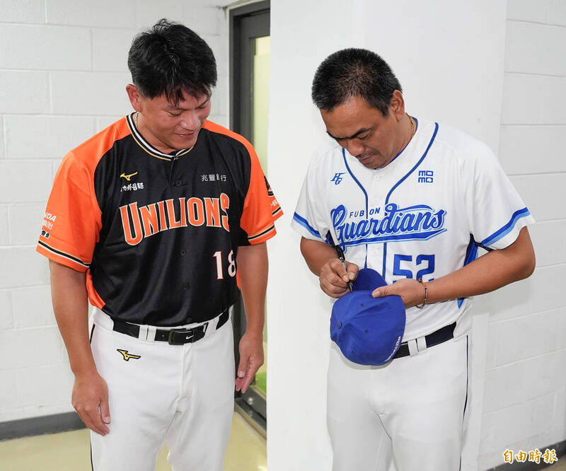 統一獅潘威倫（左）拿著球帽請富邦悍將總教練陳金鋒（右）簽名。（記者陳志曲攝）