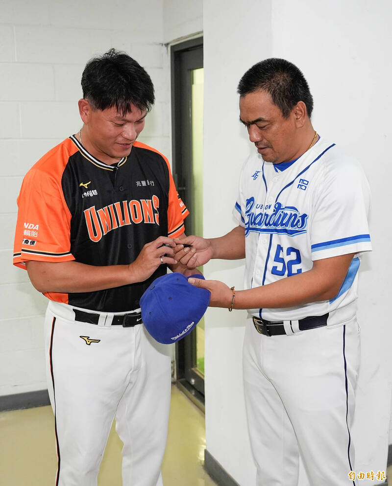 統一獅潘威倫（左）拿著球帽請富邦悍將總教練陳金鋒（右）簽名。（記者陳志曲攝）