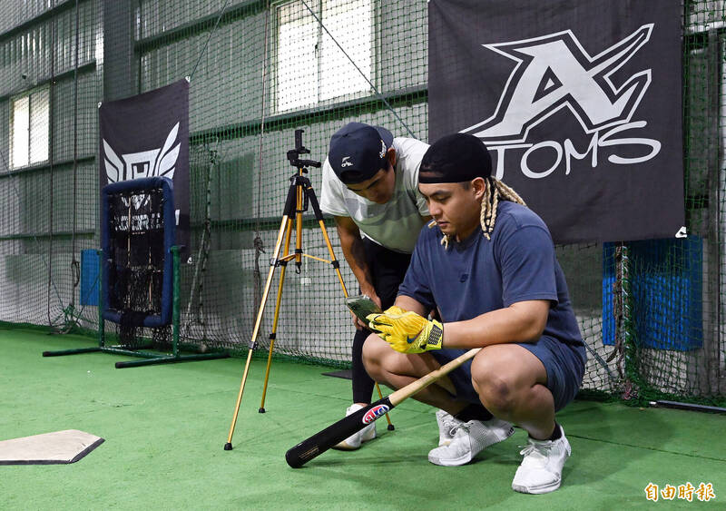 林子偉與吉力吉撈·鞏冠觀看手機檢視打擊姿勢動作。（記者李惠洲攝）