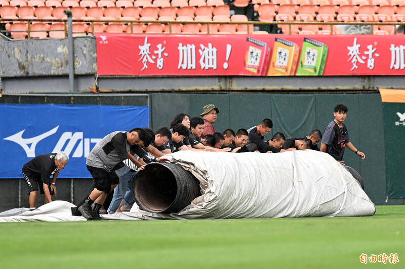 獅鷹大戰賽前因雨不停歇、蓋上帆布，確定會延後開打。（記者李惠洲攝）