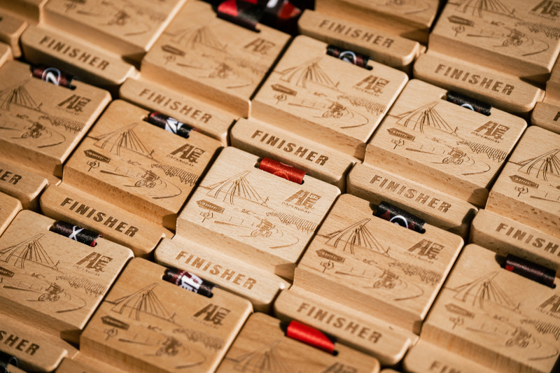 今年完賽獎牌以木材打造兼具環保與使用性的手機支架獎牌。（LAVA鐵人公司提供）