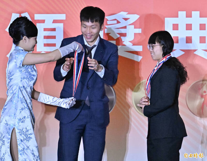 舉重選手陳冠伶（右）表現優異，拿下12面國光體育獎章，運動部部長李洋（中）幫她掛獎牌的時候露出燦爛笑容。（記者陳志曲攝）