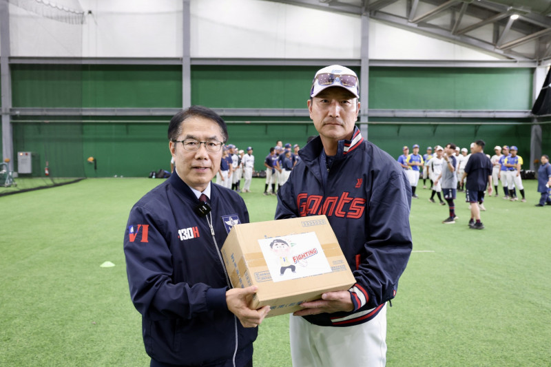 台南市長黃偉哲（左）贈送樂天巨人首席教練姜錫千（右）補給能量飲料。（南市體育局提供）