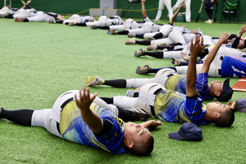 年輕球員們接受指導前先做伸展暖身。（南市體育局提供）