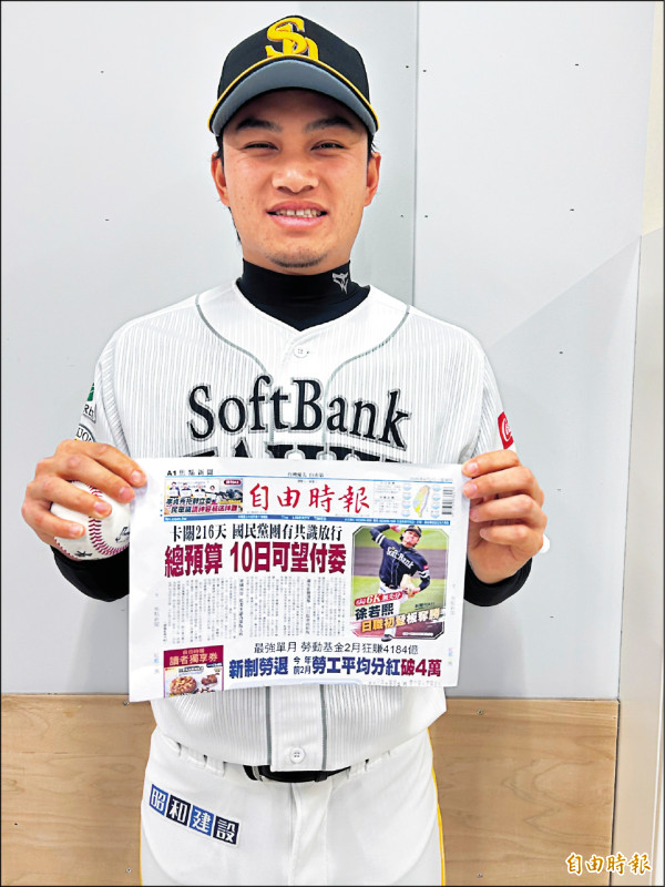 徐若熙拿著首勝球和本報報導首勝版面。（特派記者倪婉君攝）