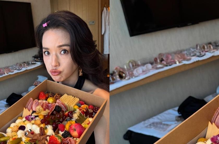 網友從背後滿桌的彩妝品和頭上髮夾「破案」，她正在梳化準備工作，美食當前只能看。