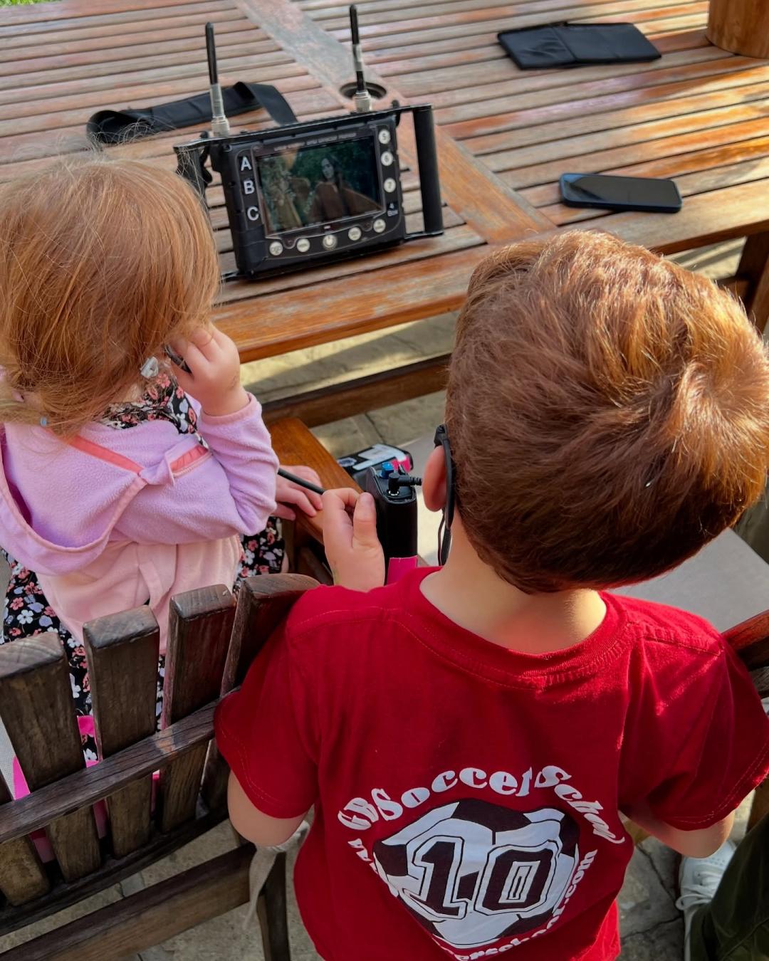 6歲阿奇、4歲莉莉貝戴著耳機看著媽媽出現在小螢幕中。