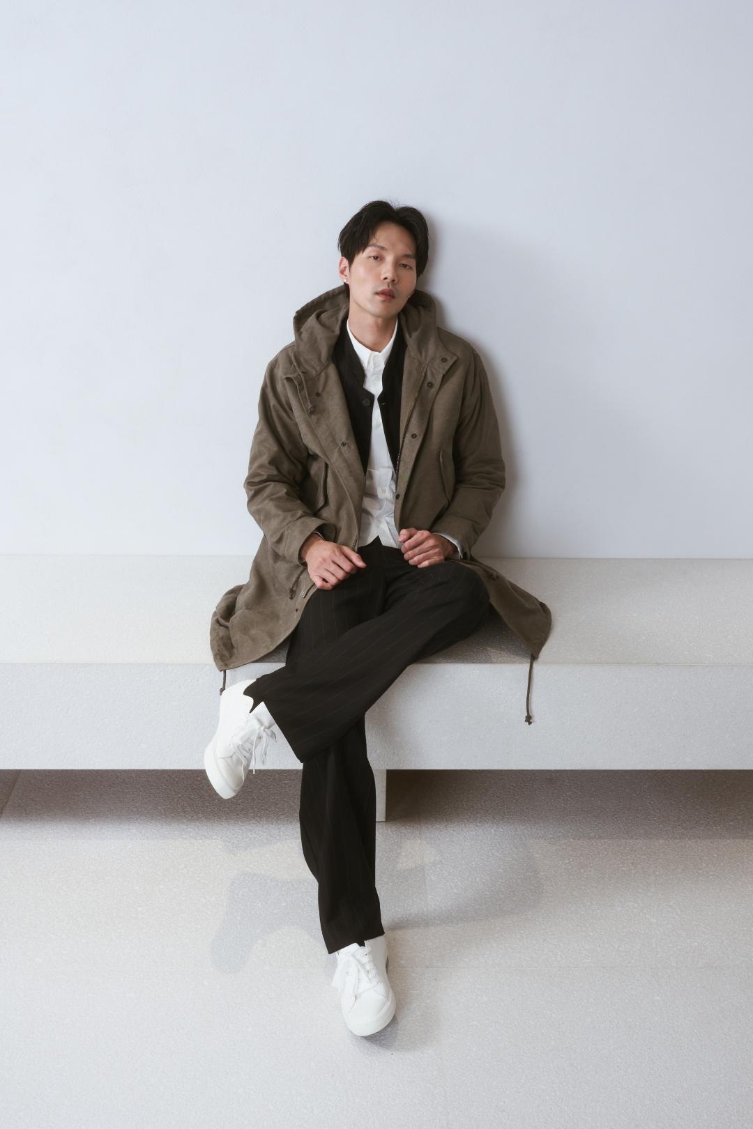 漠沙色抽繩連帽風衣搭配午夜藍條紋西裝外套與牛津襯衫，營造出具有豐富層次的沈穩內斂風格。