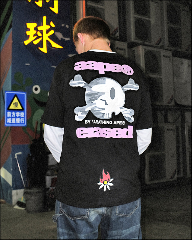 AAPE×ERASED聯名系列短袖T恤，迷彩骷髏猿人頭搭配粉嫩「aaperased」字樣，打造強烈視覺反差，背後燃燒雛菊細節更添叛逆潮流感，2,709元。