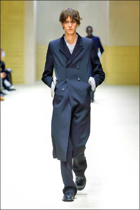 管狀剪裁的雙排釦大衣採收窄肩線設計，整體線條更貼近身體姿態，為正裝造型帶來當代詮釋。