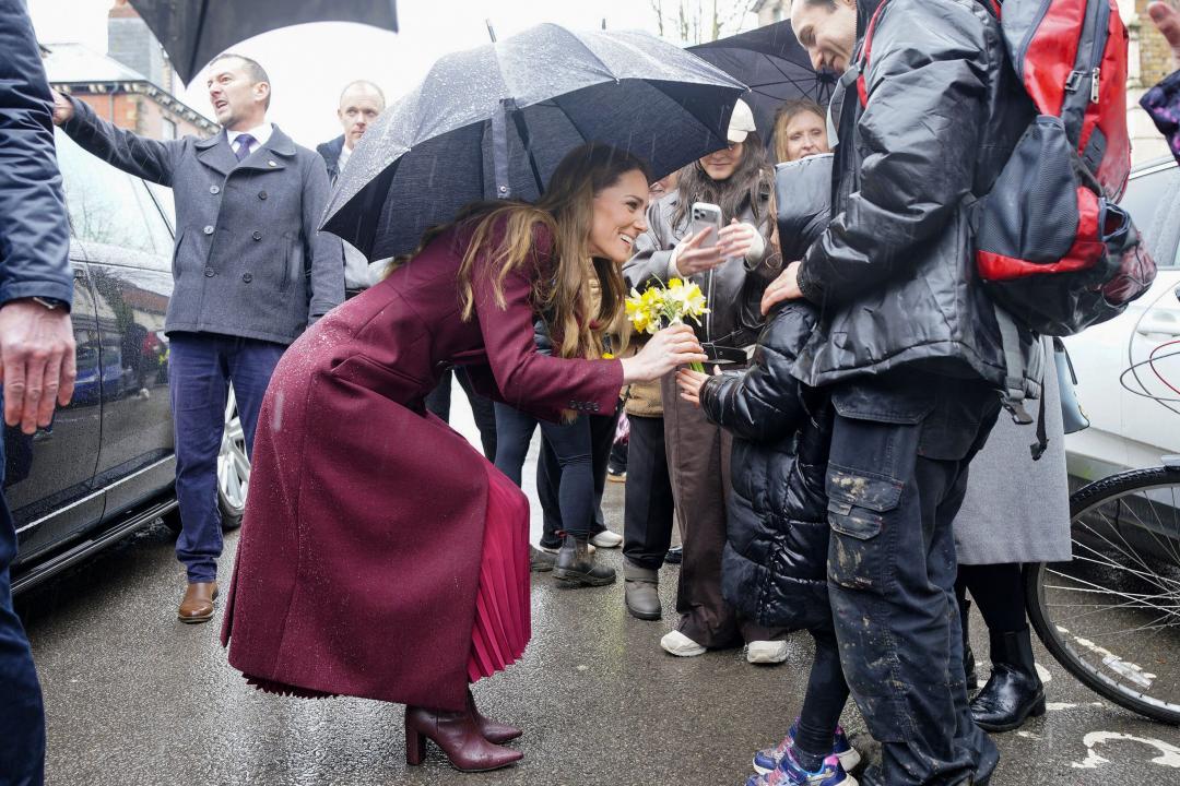 凱特王妃蹲下身子和孩童打招呼，被雨淋濕。(法新社)
