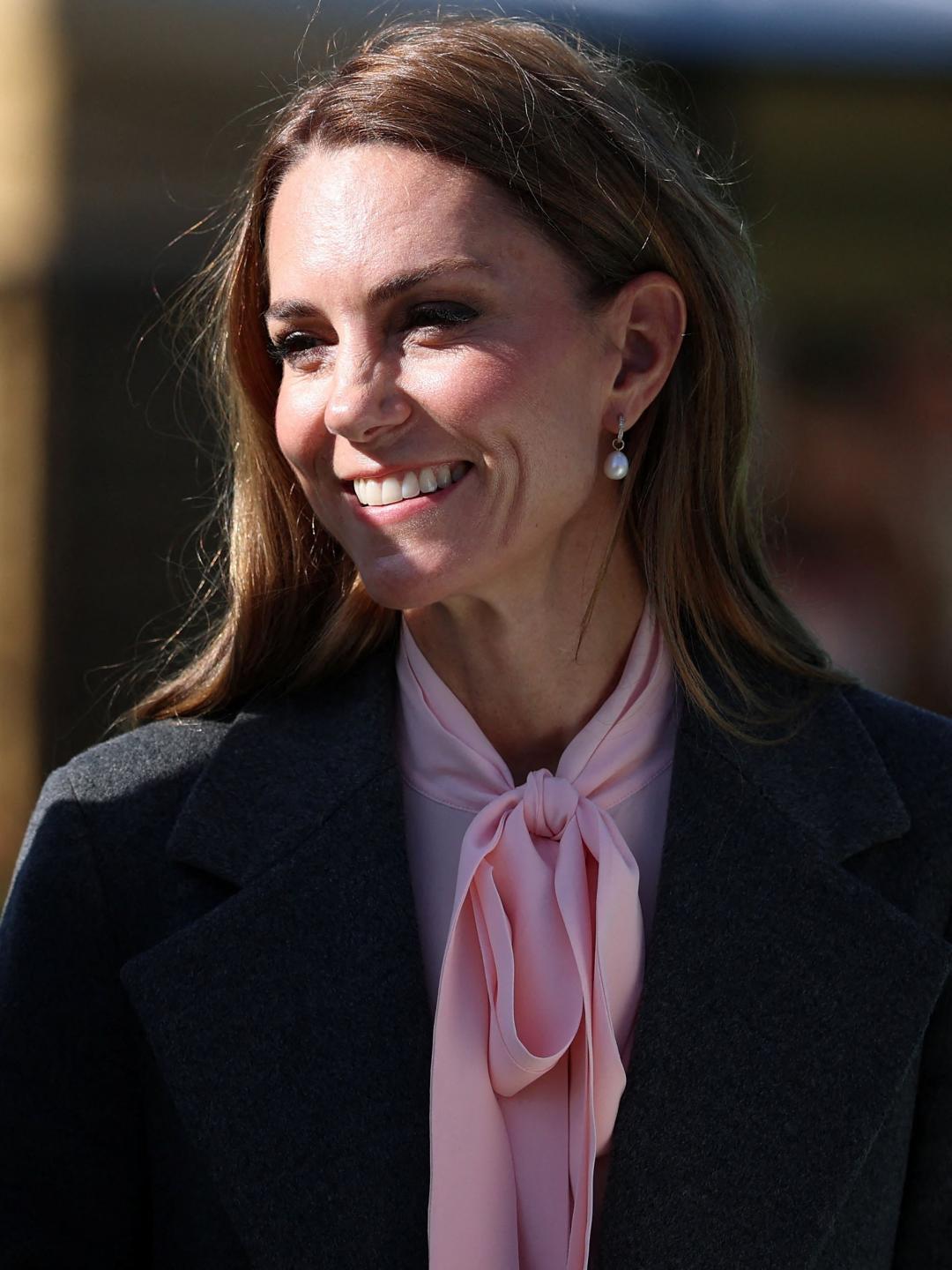 粉紅色蝴蝶結襯衫搭配灰色大衣，優雅幹練。(法新社)