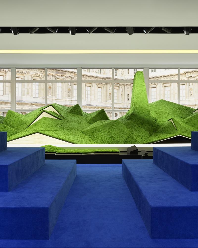 秀場設於巴黎羅浮宮Cour Carrée方形庭院，以抽象綠色山景打造未來自然景觀，營造模特兒穿梭山林的沉浸式場景。（Louis Vuitton提供）