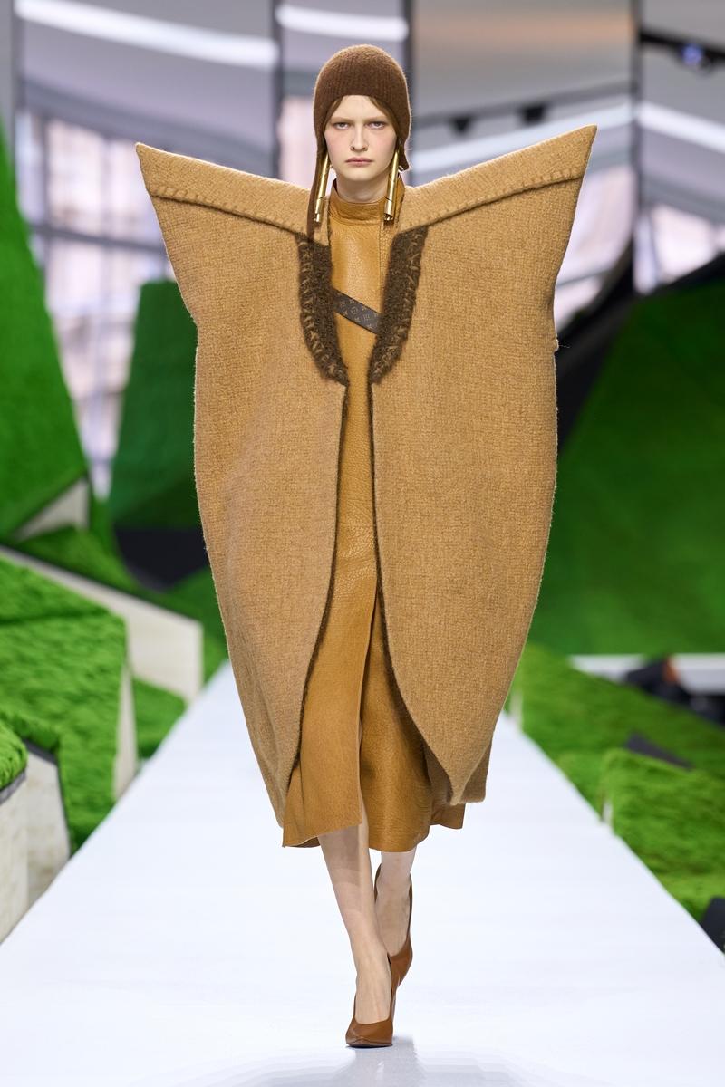 立體披肩式輪廓外套以大地色調呈現，誇張肩線與包覆式結構展現服裝建築輪廓的實驗性詮釋。（Louis Vuitton提供）