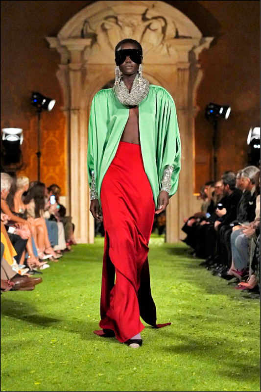 湖水綠披風式外套搭配紅色長裙，透過高飽和撞色呈現強烈視覺張力。