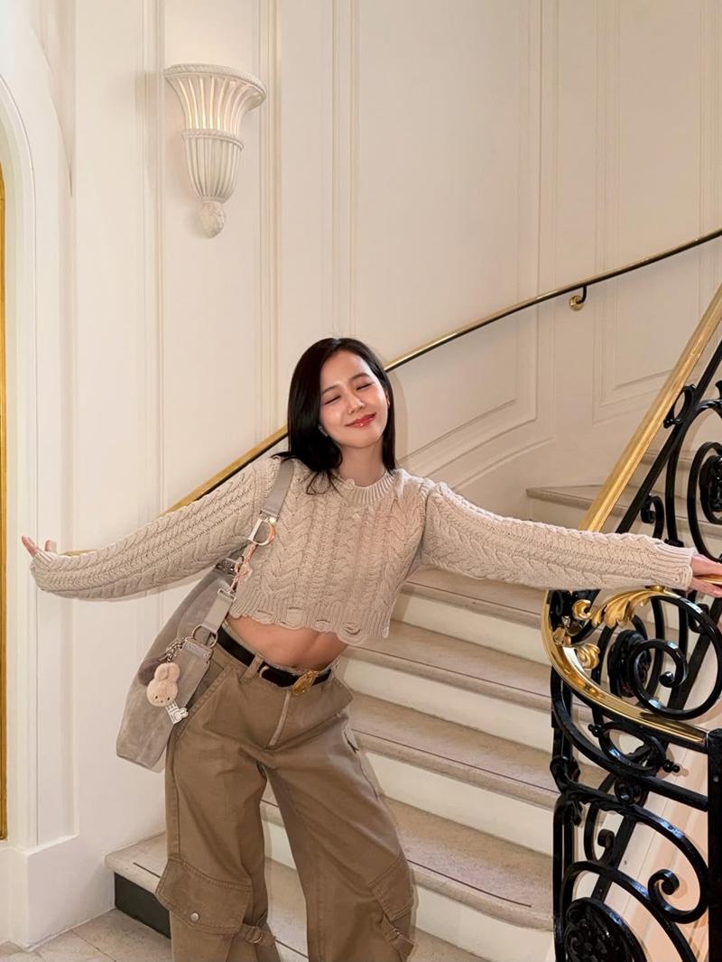 Jisoo身穿米色針織上衣與寬褲搭配Diorly包款，並掛上吊飾展現俏皮私服風格。（Dior提供）