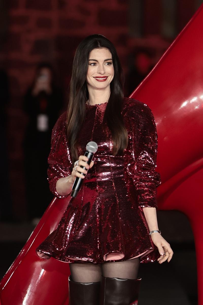 安海瑟薇身著Stella McCartney亮粉色亮片短裙與長靴，展現俐落又大膽的時尚態度。（歐新社）